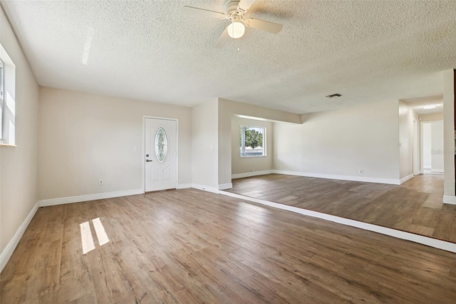 unfurnished living room with wood-type flooring, a textured ceiling, and ceiling fan