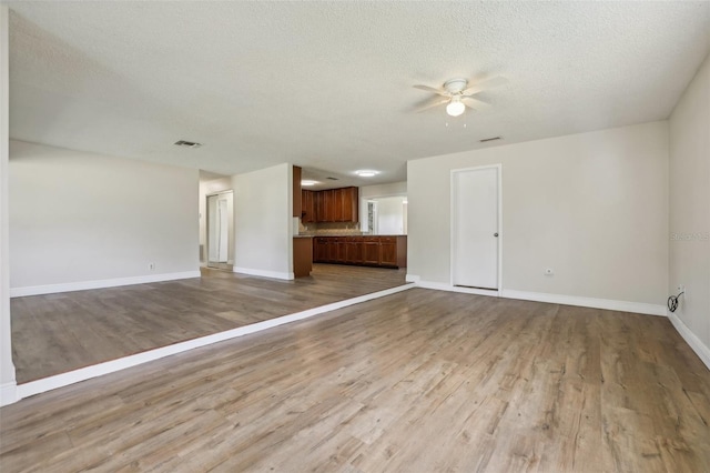 unfurnished living room featuring a textured ceiling, ceiling fan, and light hardwood / wood-style flooring