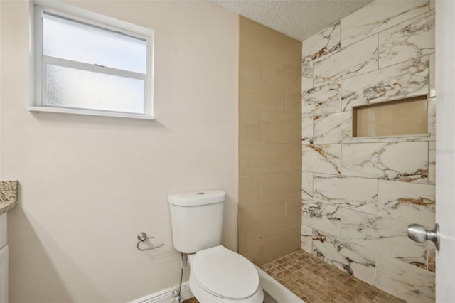 bathroom featuring a textured ceiling, a tile shower, and toilet