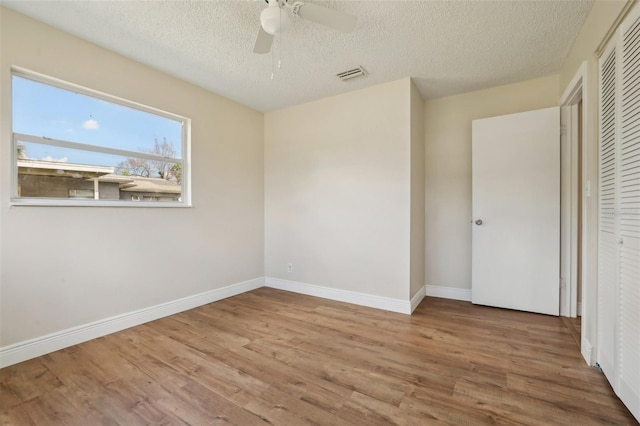 unfurnished bedroom featuring a textured ceiling, ceiling fan, a closet, and light hardwood / wood-style flooring