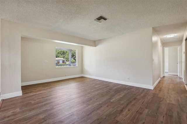 empty room featuring a textured ceiling and dark hardwood / wood-style floors