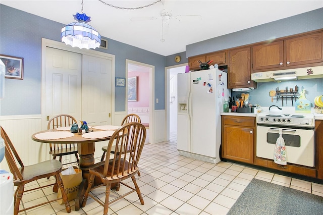 kitchen featuring white appliances, pendant lighting, ceiling fan, range hood, and light tile flooring