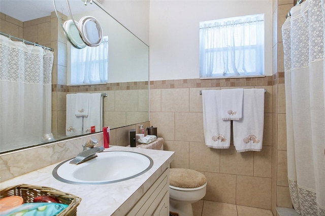 bathroom featuring toilet, tile flooring, oversized vanity, and tile walls