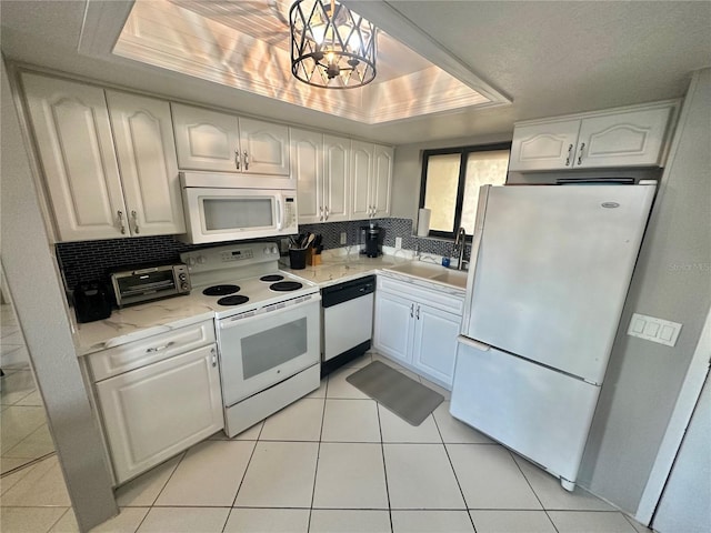 kitchen featuring white appliances, a notable chandelier, white cabinets, and a tray ceiling