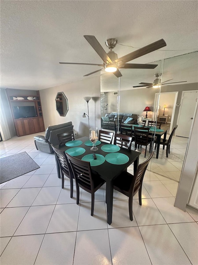 dining space featuring light tile flooring, ceiling fan, and a textured ceiling