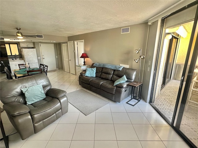 tiled living room with a textured ceiling, ceiling fan, and sink