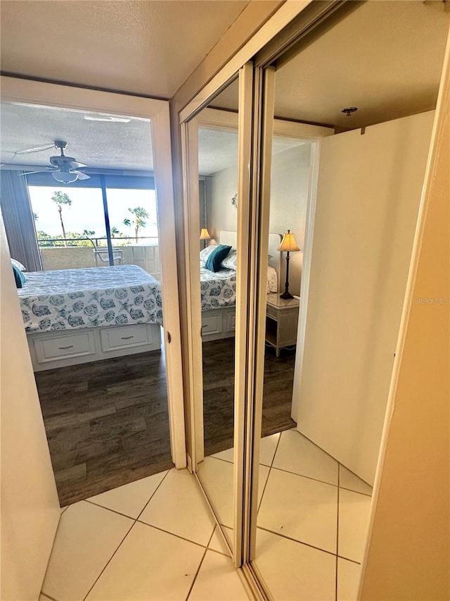 corridor featuring light tile flooring and a textured ceiling