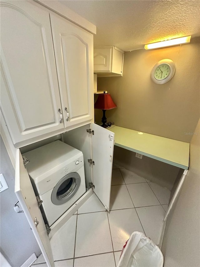 clothes washing area with light tile floors, cabinets, a textured ceiling, and washer / dryer