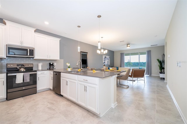 kitchen with sink, stainless steel appliances, white cabinets, a chandelier, and pendant lighting