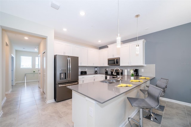 kitchen featuring kitchen peninsula, hanging light fixtures, appliances with stainless steel finishes, white cabinets, and a breakfast bar area