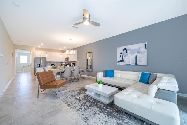 living room featuring light tile floors and ceiling fan with notable chandelier