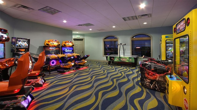 playroom with dark colored carpet and a drop ceiling