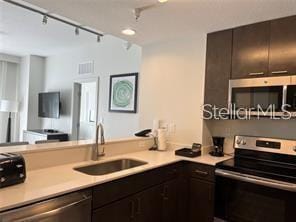 kitchen featuring dark brown cabinetry, appliances with stainless steel finishes, track lighting, and sink