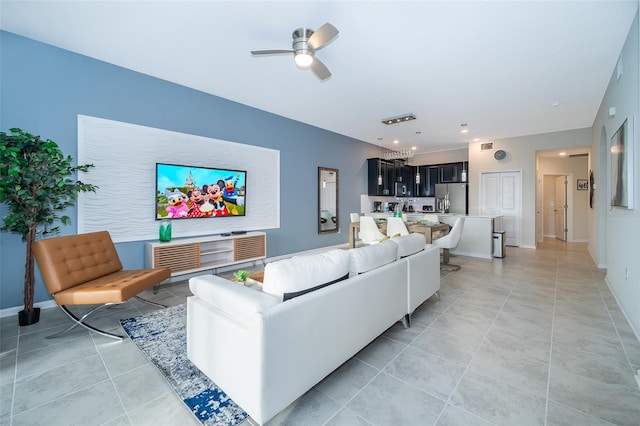 tiled living room featuring ceiling fan with notable chandelier