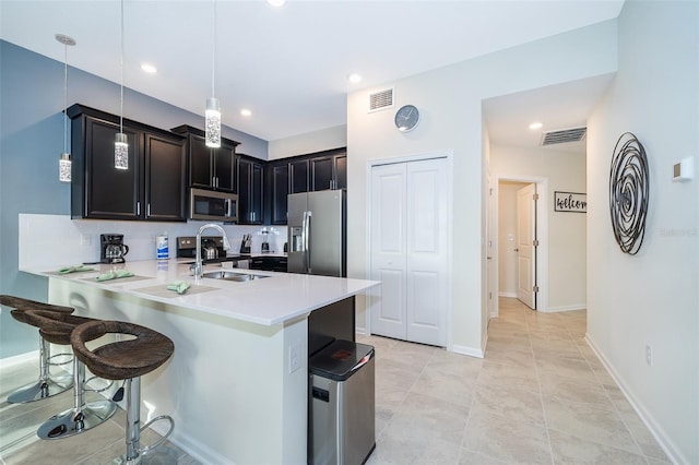 kitchen featuring sink, a breakfast bar area, stainless steel appliances, light tile flooring, and decorative light fixtures