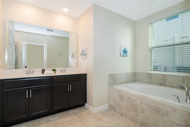 bathroom with a relaxing tiled bath, double sink, tile floors, and vanity with extensive cabinet space