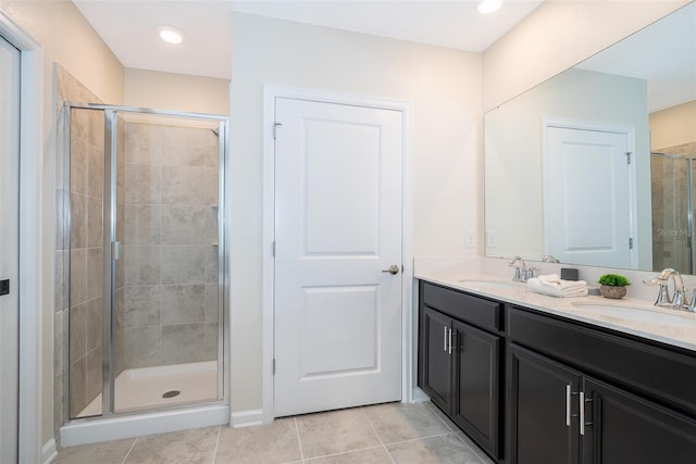 bathroom featuring a shower with shower door, double sink, vanity with extensive cabinet space, and tile flooring