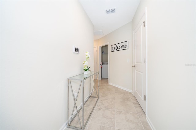 hallway with light tile floors and washer / dryer