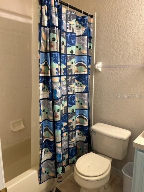 full bathroom featuring tile patterned flooring, shower / bath combo, toilet, and vanity