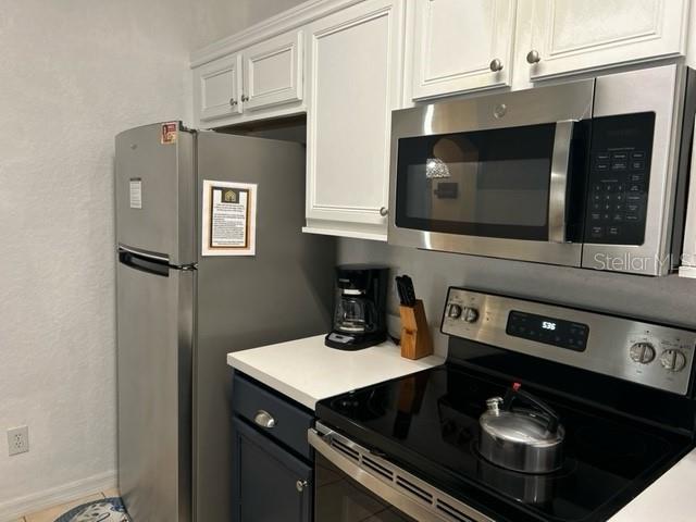 kitchen featuring tile patterned flooring, appliances with stainless steel finishes, and white cabinetry