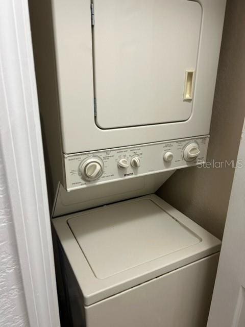 washroom featuring stacked washer / drying machine