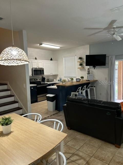 kitchen with ceiling fan, light tile patterned flooring, decorative light fixtures, white cabinets, and appliances with stainless steel finishes