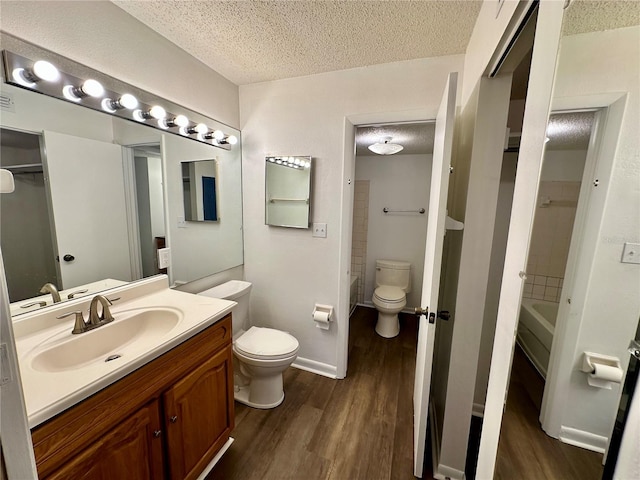 full bathroom featuring hardwood / wood-style flooring, shower / washtub combination, a textured ceiling, vanity, and toilet