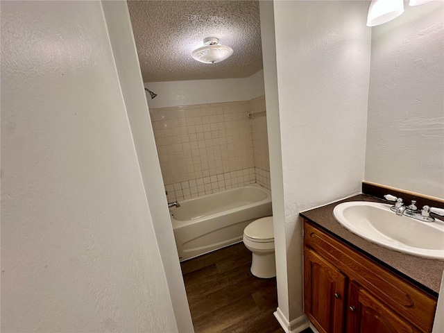 full bathroom featuring vanity, a textured ceiling, tiled shower / bath, toilet, and hardwood / wood-style flooring