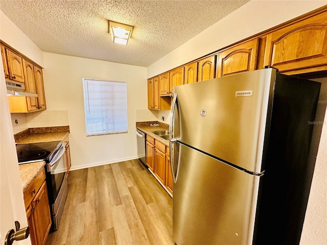 kitchen with decorative backsplash, light hardwood / wood-style floors, sink, a textured ceiling, and stainless steel appliances