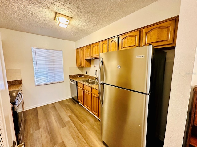 kitchen with sink, light wood-type flooring, a textured ceiling, and stainless steel appliances