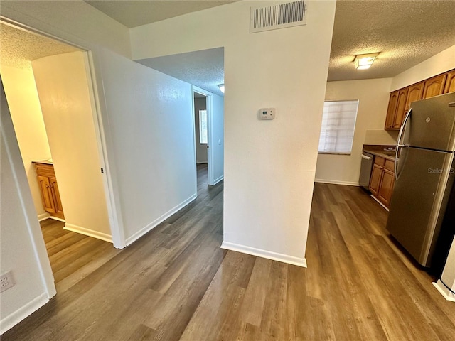 kitchen featuring a textured ceiling, hardwood / wood-style floors, and stainless steel appliances