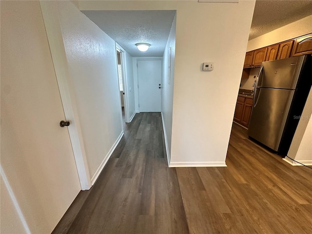 corridor featuring a textured ceiling and dark hardwood / wood-style flooring