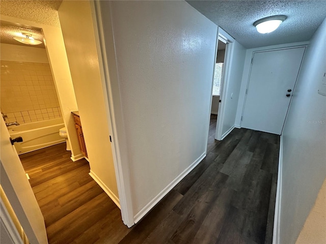 corridor featuring a textured ceiling and dark wood-type flooring