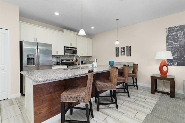 kitchen featuring a breakfast bar, appliances with stainless steel finishes, backsplash, and light stone countertops