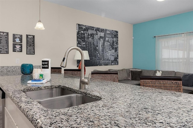 kitchen featuring pendant lighting, sink, and light stone counters