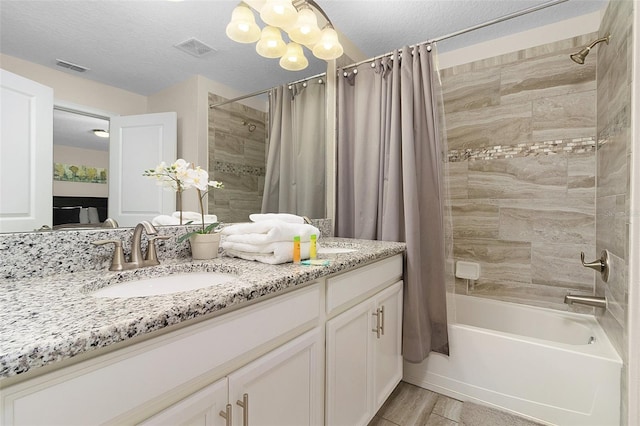 bathroom featuring vanity, a textured ceiling, a chandelier, and shower / bath combo