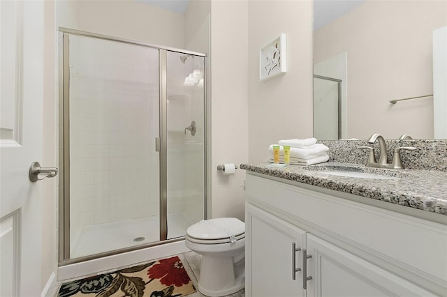 bathroom featuring toilet, a shower with door, tile floors, and large vanity