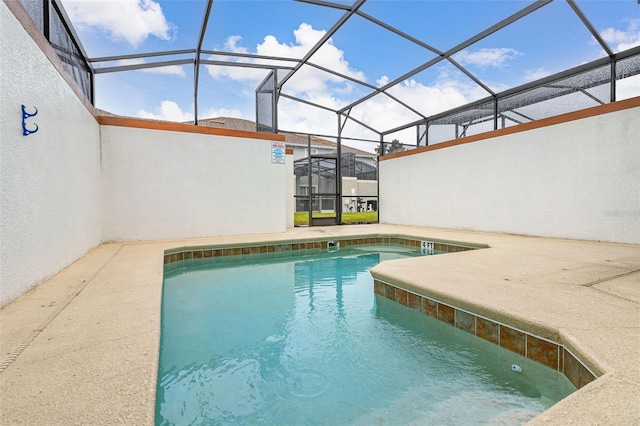 view of pool featuring glass enclosure and a patio