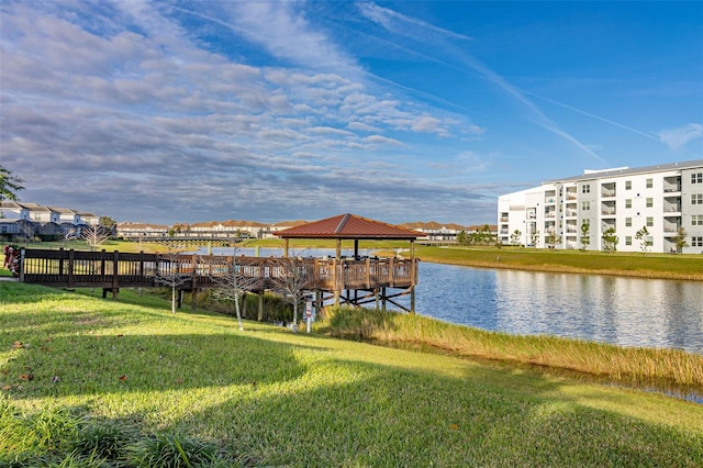 dock area with a gazebo, a water view, and a lawn