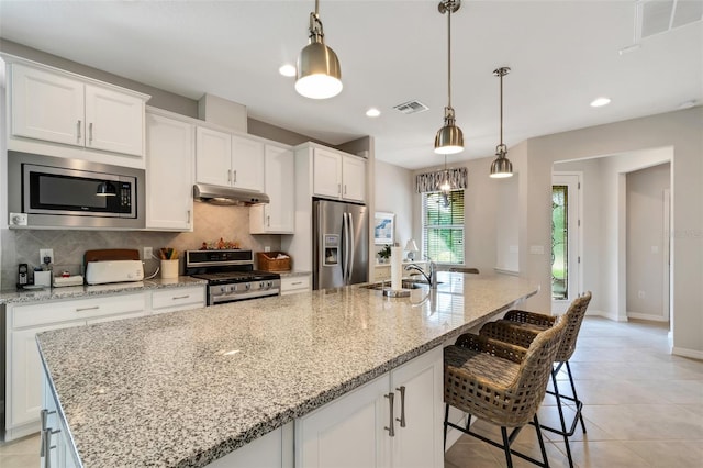 kitchen with a center island with sink, white cabinetry, decorative light fixtures, and stainless steel appliances