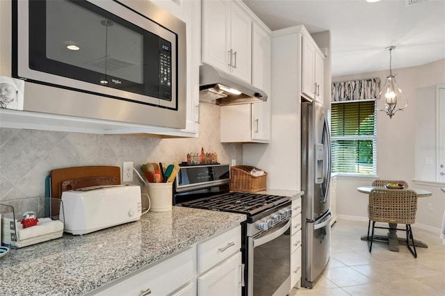 kitchen featuring tasteful backsplash, appliances with stainless steel finishes, white cabinetry, hanging light fixtures, and light stone counters