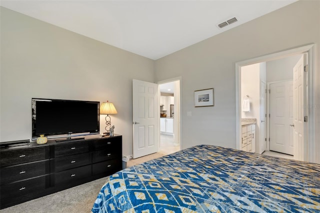 bedroom featuring light carpet and ensuite bath