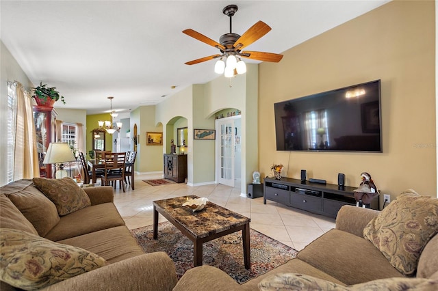 tiled living room featuring ceiling fan with notable chandelier