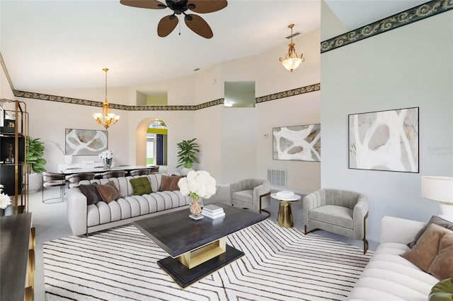 carpeted living room with high vaulted ceiling and ceiling fan with notable chandelier