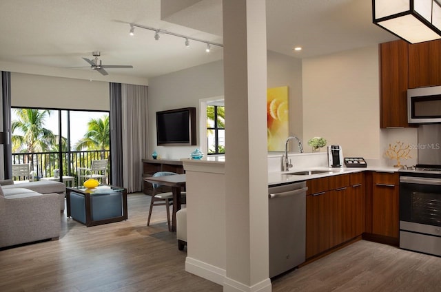 kitchen featuring sink, rail lighting, light wood-type flooring, and stainless steel appliances