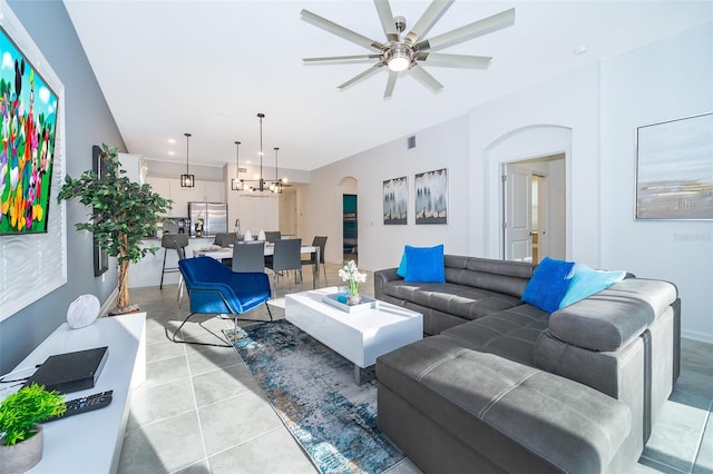 tiled living room featuring ceiling fan with notable chandelier