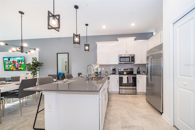 kitchen with sink, hanging light fixtures, white cabinets, appliances with stainless steel finishes, and an inviting chandelier