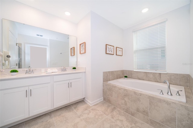 bathroom featuring tiled bath, double sink, vanity with extensive cabinet space, and tile flooring