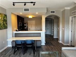 kitchen with arched walkways, a breakfast bar, visible vents, and baseboards