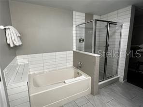 full bathroom with a stall shower, a bath, and tile patterned floors